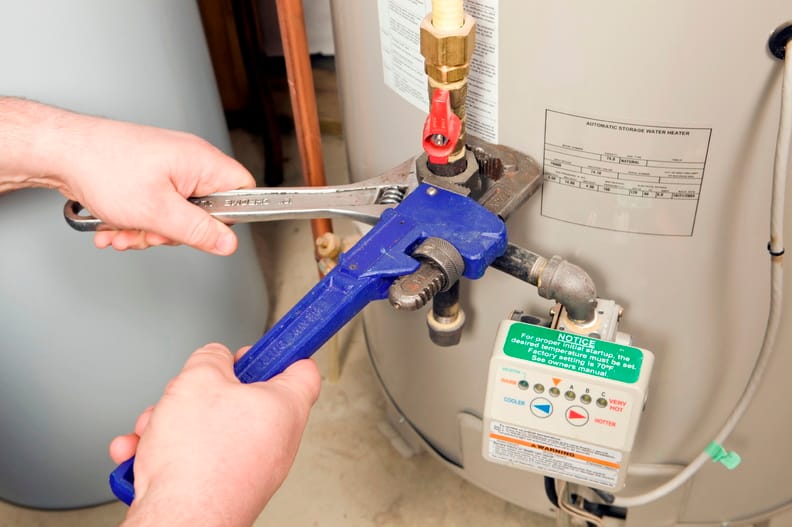 Plumber repairing water heater pipe connection in Woodstock, Georgia home
